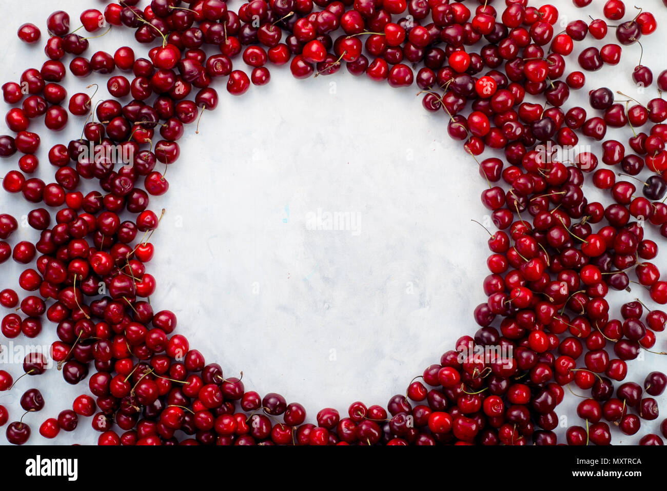 Vignette de cerise, cerises fraîches dispersées sur fond de marbre blanc avec un cercle. Fond d'aliments sains Vue supérieure avec copie espace. Banque D'Images