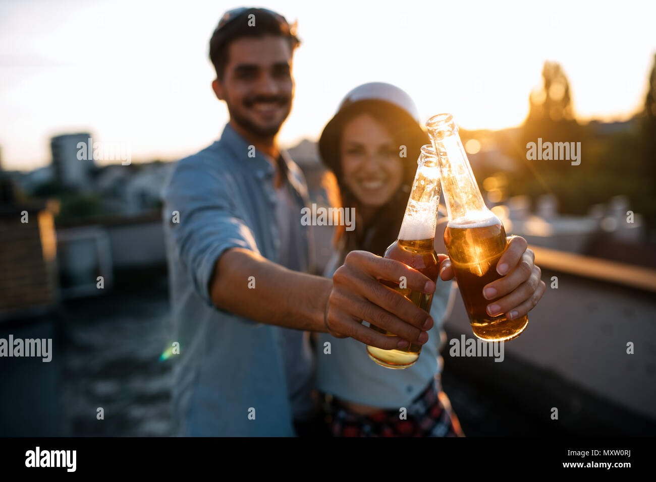 Young happy couple toasting with beer outdoors Banque D'Images