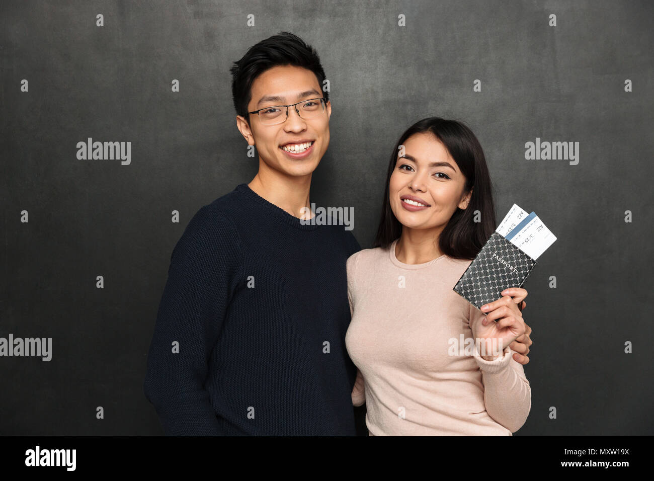 Happy asian couple posing together et la préparation de voyage en regardant la caméra sur fond noir Banque D'Images
