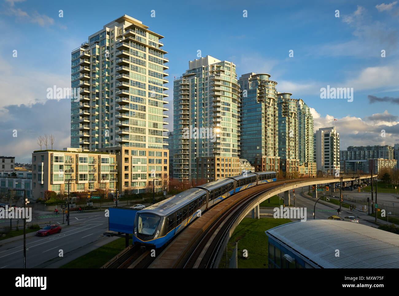 Transport ferroviaire de banlieue de Vancouver une élévation des vitesses de voiture le long d'une piste. Tours de condominiums en arrière-plan. Banque D'Images