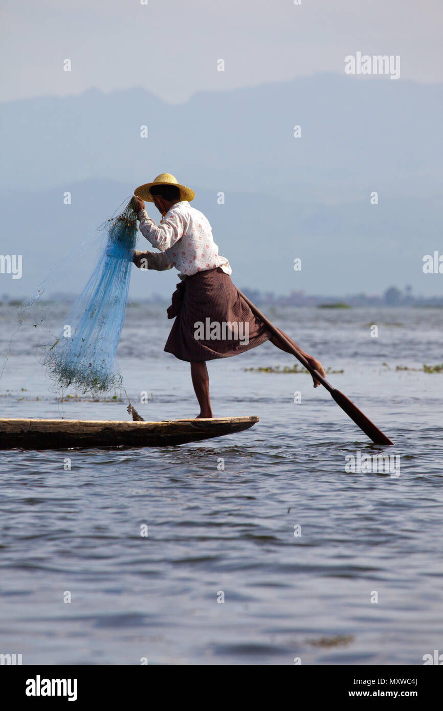 Un pêcheur local distinctif démontrant la technique d'aviron de la jambe au Lac Inle, en Birmanie. Banque D'Images