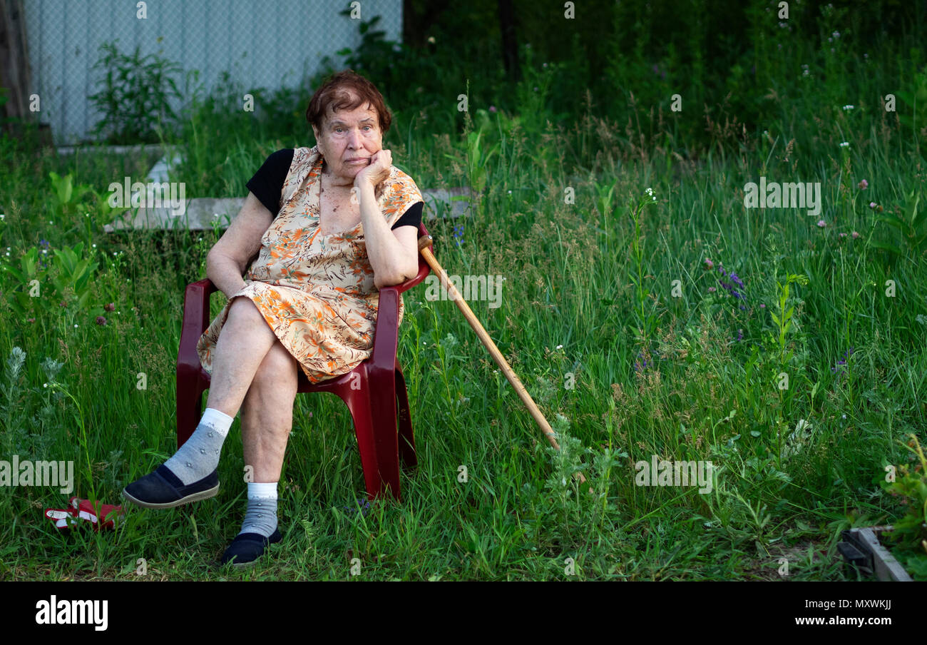 Personnes âgées caucasian woman assis dans un fauteuil en plastique dans le jardin Banque D'Images