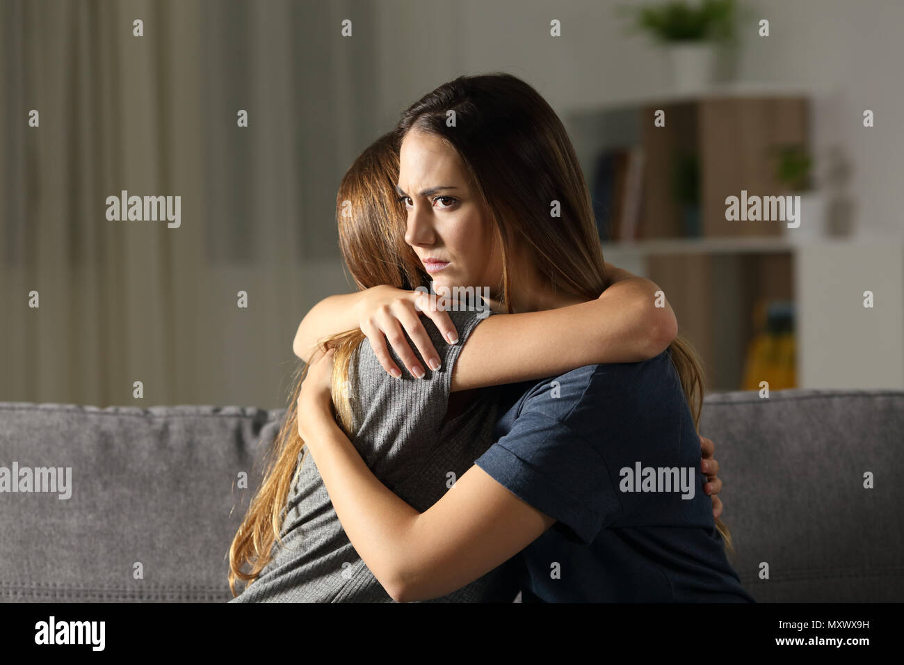 Angry woman hugging un ami assis sur un canapé dans la salle de séjour à la maison Banque D'Images