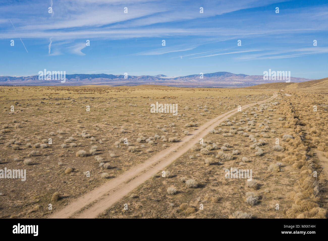 Vue aérienne de route de terre qui longe une clôture métallique dans la grande plaines arides de la Californie centrale. Banque D'Images