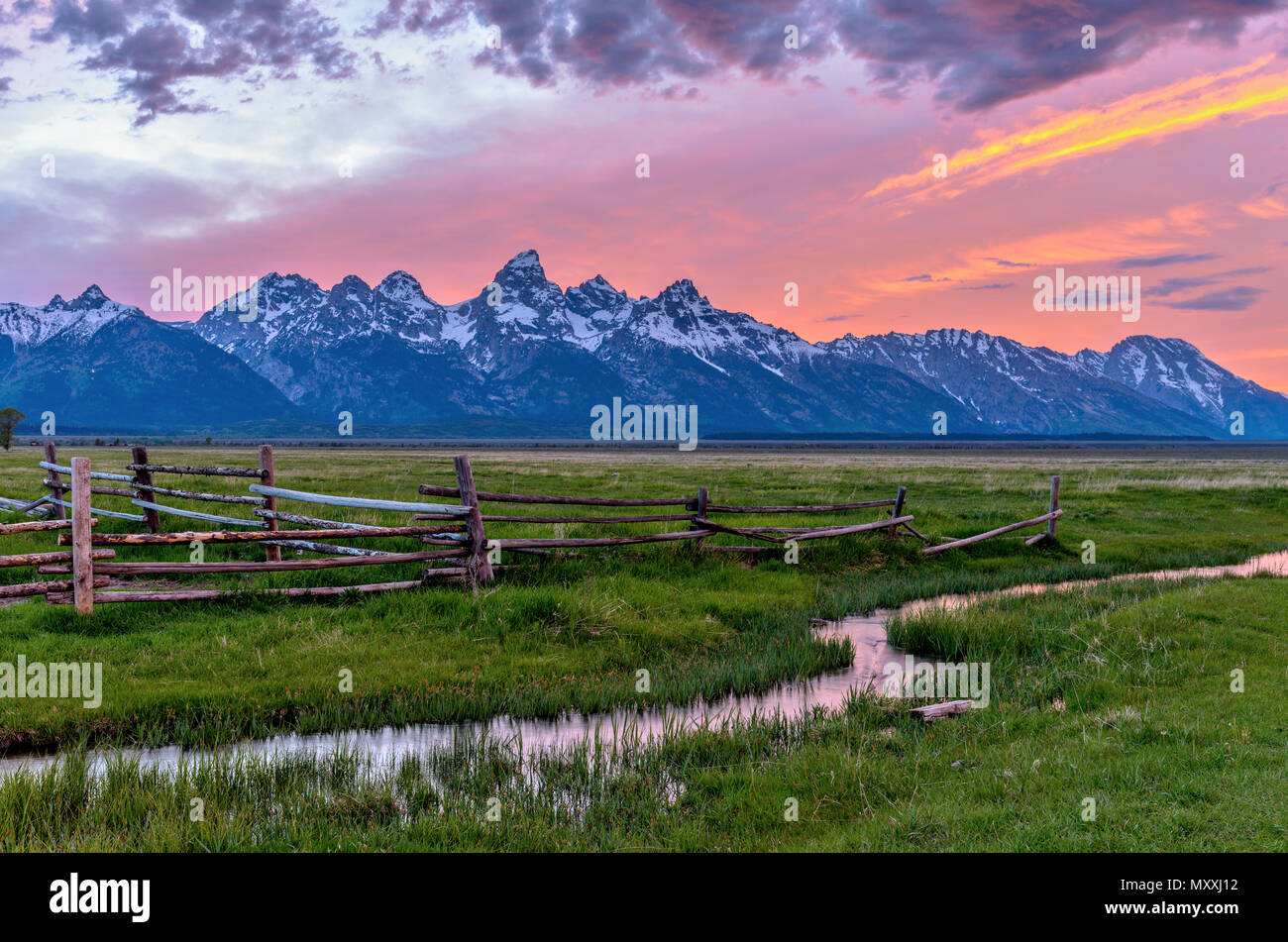 Coucher du soleil à Teton Range - une vue sur le coucher de soleil de printemps de Teton Range, avec des clôtures rouillées et la liquidation d'un ancien cours d'eau de drainage dans la région de ranch à l'avant ligne Mormon. Banque D'Images