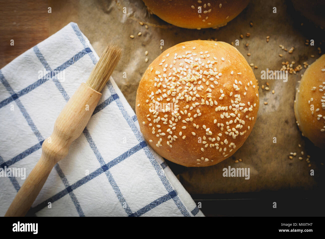 Vue de dessus des pains de sésame sur une planche en bois avec un chiffon blanc à rayures cuisine et d'un pinceau. Le format paysage. Banque D'Images