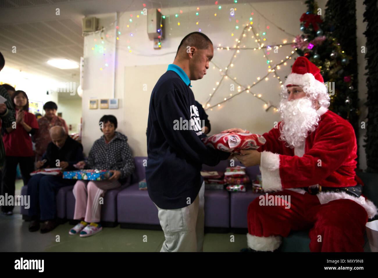 Un Reimei no Sato accueil résident reçoit un cadeau du Père Noël lors d'une  visite de membres de service d'un camp Hansen le 16 décembre à Ishikawa,  Okinawa, Japon. L'Reimei no Sato