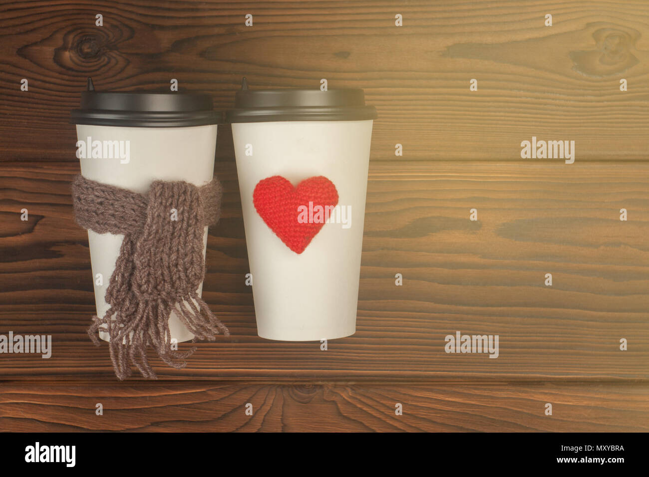 Deux tasses de café pour aller dans du papier blanc tasses dans la lumière du soleil. Café du matin pour un couple dans l'amour. Coeur de tricot et écharpe. Place pour le texte. Photo couleur Banque D'Images