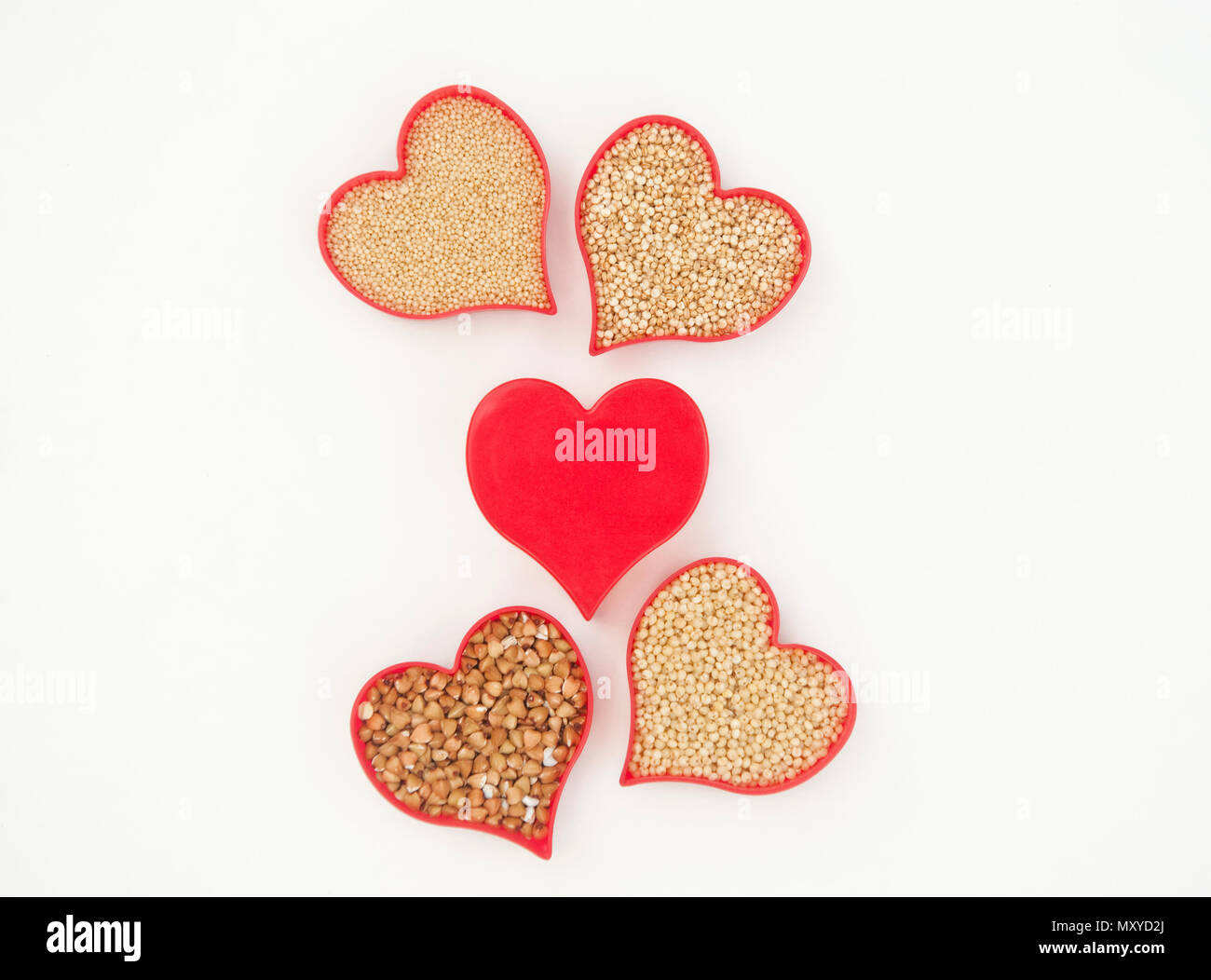 Le quinoa, amarante, millet et sarrasin rempli coeurs entourant un cœur rouge sur blanc Banque D'Images