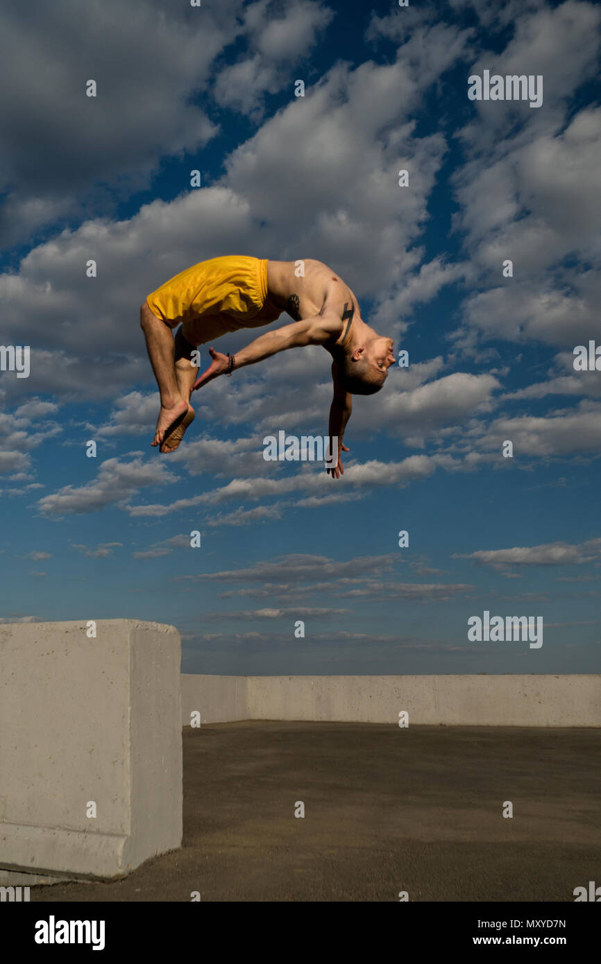 Donnant sur la rue. Arts martiaux et d'éléments du parkour. L'homme se retourne en arrière, pieds nus. Filmé à partir du fond du ciel contre l'effet de rapprochement. Banque D'Images