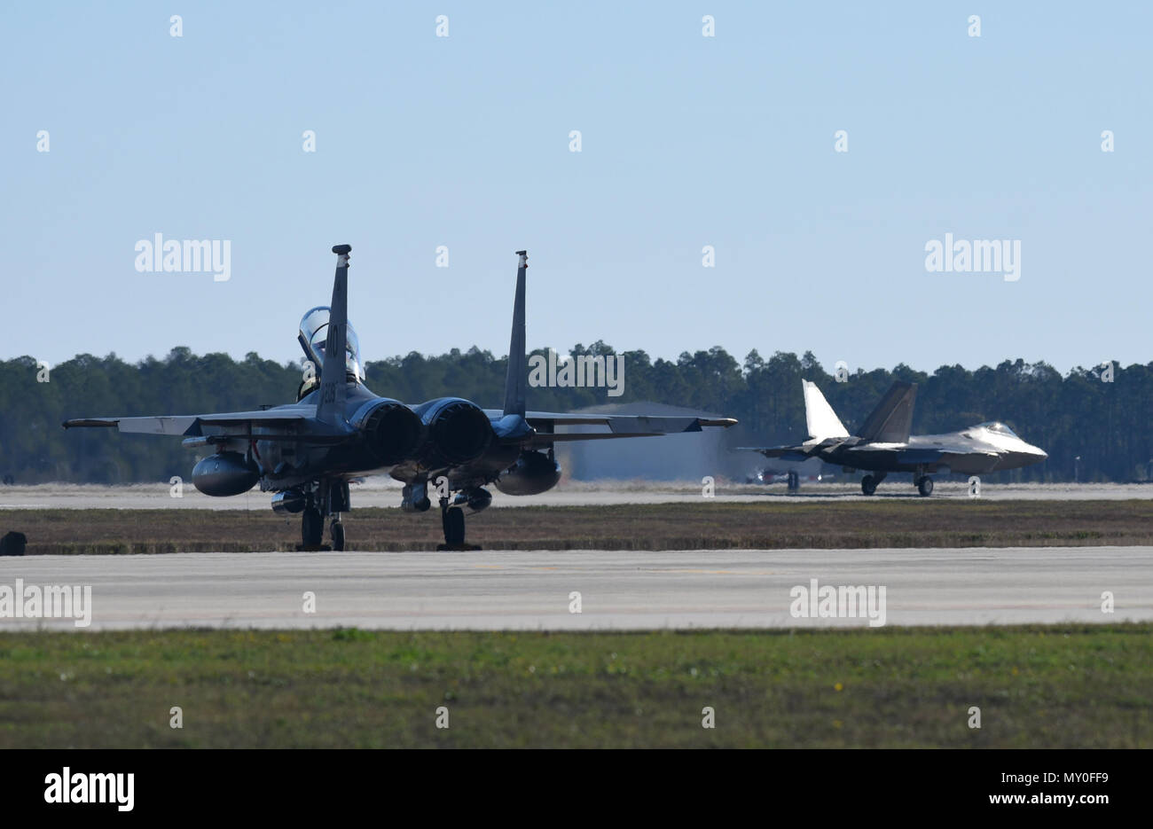 Un U.S. Air Force F-15E Strike Eagle à Mountain Home Air Force Base, Texas, est assis à la main alors qu'un F-22 Raptor Tyndall passe au cours de drapeau à damiers 17-1 à la base aérienne Tyndall, en Floride, le 16 décembre 2016. Au cours de l'exercice, quatrième et cinquième génération de pilotes de chasse ont travaillé ensemble pour remplissez des missions impliquant de multiples cellules y compris le F-35A Lightning II, F-22, F-16CM Fighting Falcon, F-15E Strike Eagle, HH-60G Pave Hawk et E-3 Sentry cellules. (U.S. Photo de l'Armée de l'air par le sergent d'Alex Fox Echols III/libérés) Banque D'Images