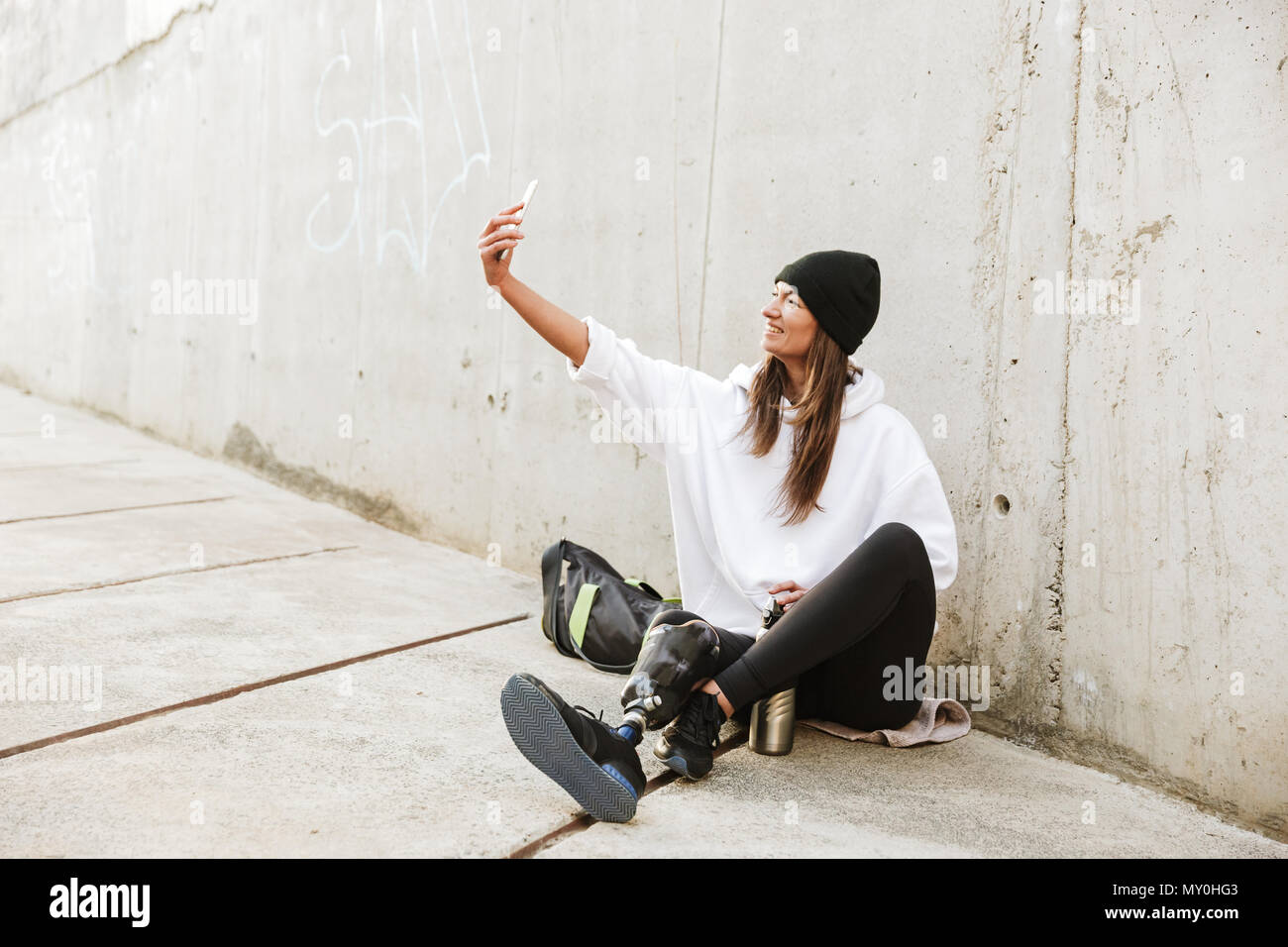 Photo de jeune femme moderne handicapés en streetwear avoir jambe bionique  assis sur un sol en béton d'extérieur et de prendre sur smartphone selfies  Photo Stock - Alamy