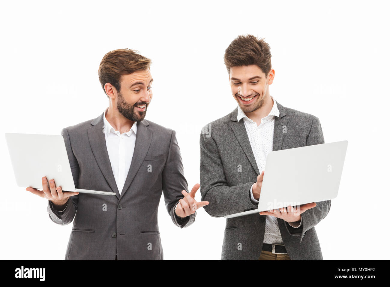 Portrait d'une entreprise deux excités des hommes travaillant sur des ordinateurs portables isolated over white background Banque D'Images