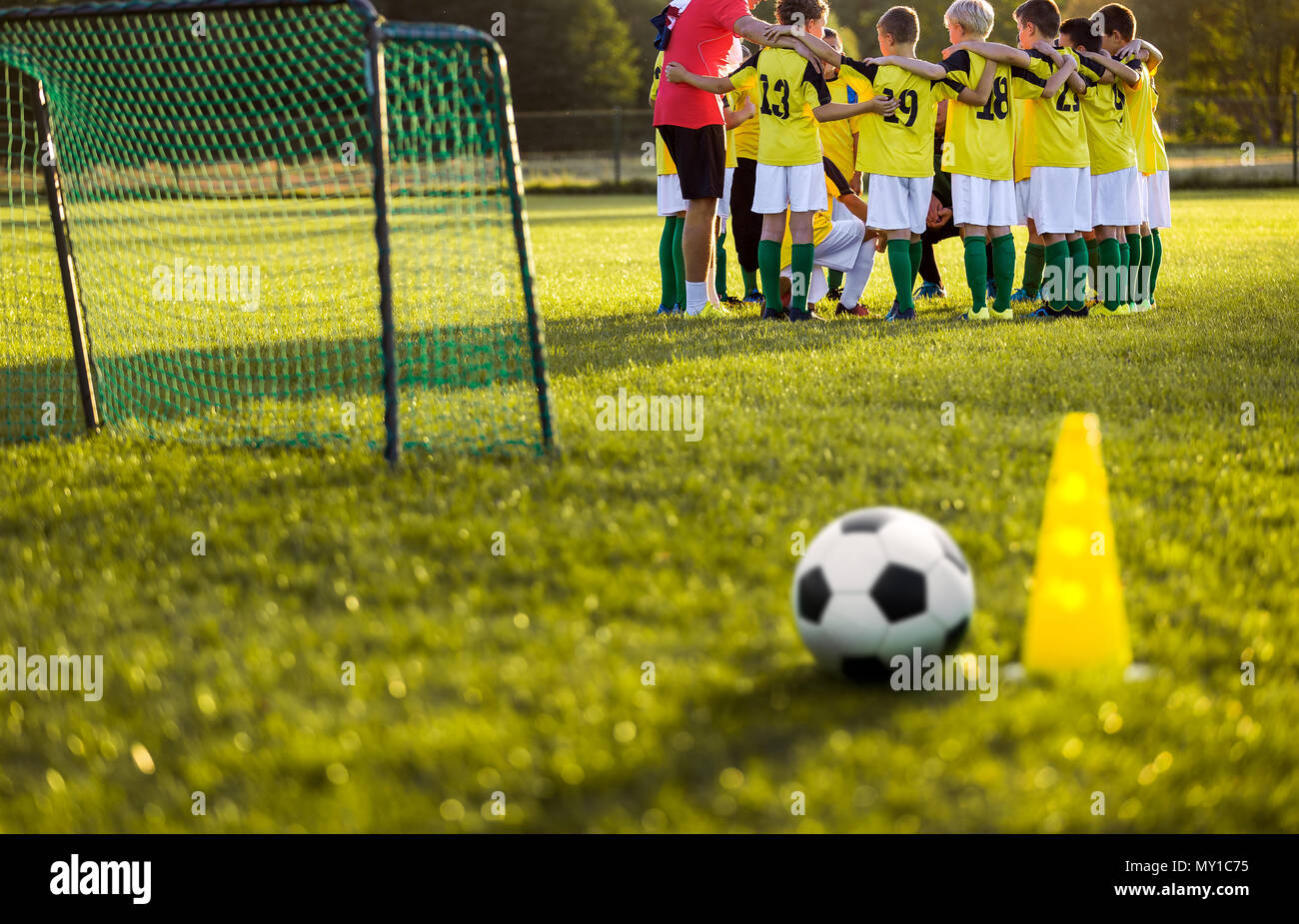 L'entraînement de football soccer pour les jeunes garçons. Session de formation sur le terrain de soccer de l'herbe. Ballon de soccer et pylône cone et buts de soccer à l'avant-plan. Vous Banque D'Images