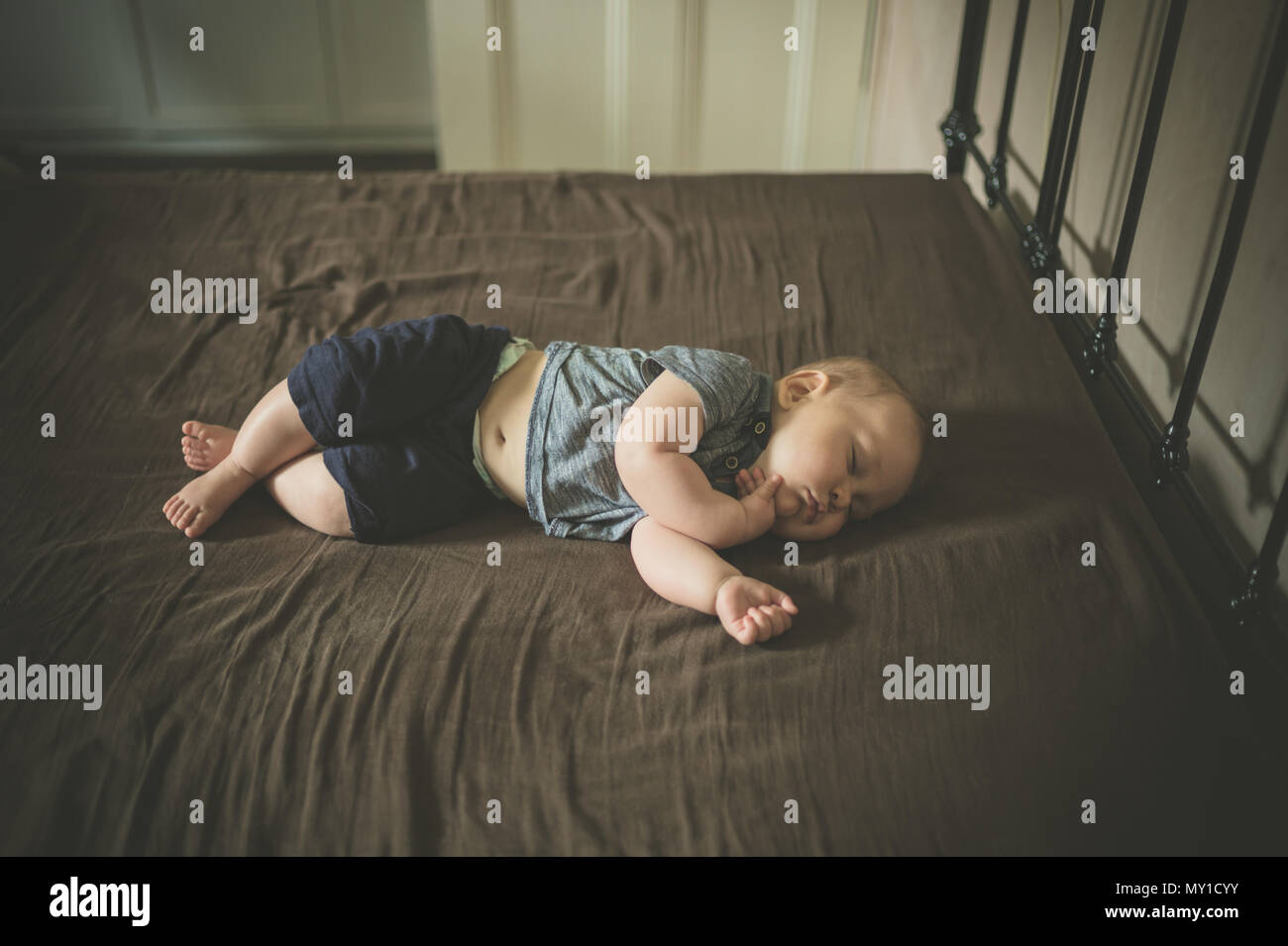 Un petit bébé est en train de dormir sur un lit Banque D'Images