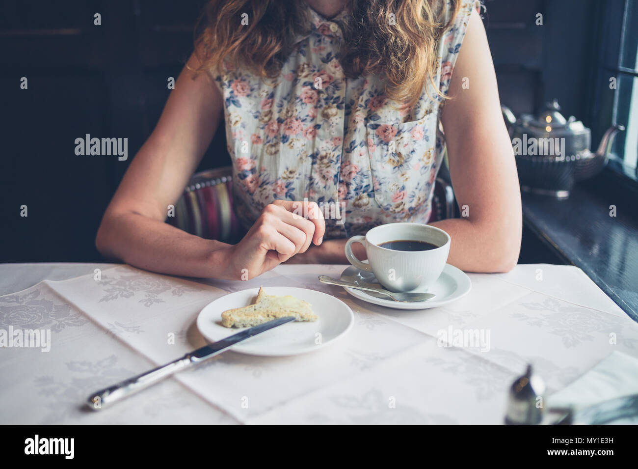 Une jeune femme est en train de manger du pain grillé avec du beurre à une table à manger Banque D'Images