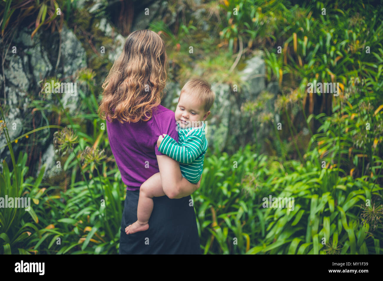 Une jeune mère est debout à l'extérieur tenant son bébé dans la nature Banque D'Images