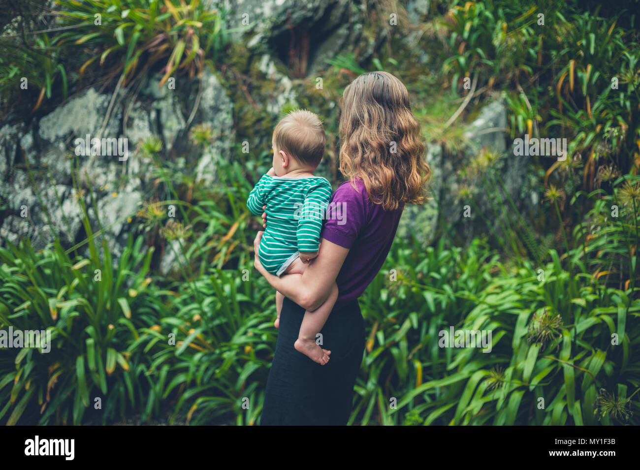 Une jeune mère est debout à l'extérieur tenant son bébé dans la nature Banque D'Images