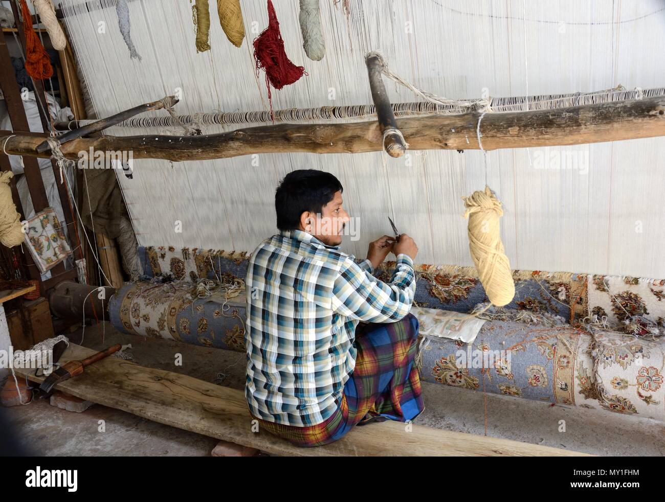 Indian homme accroupi sur le sol indien traditionnel du tissage de tapis tapis sur un métier à tisser en bois simple Rajasthan Inde Banque D'Images