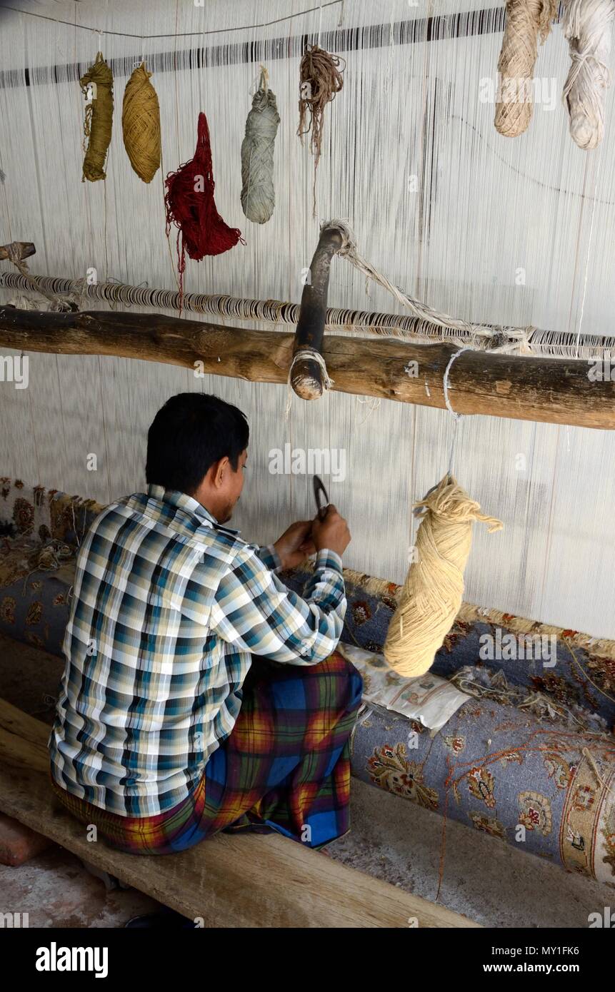 Indian homme accroupi sur le sol indien traditionnel du tissage de tapis tapis sur un métier à tisser en bois simple Rajasthan Inde Banque D'Images