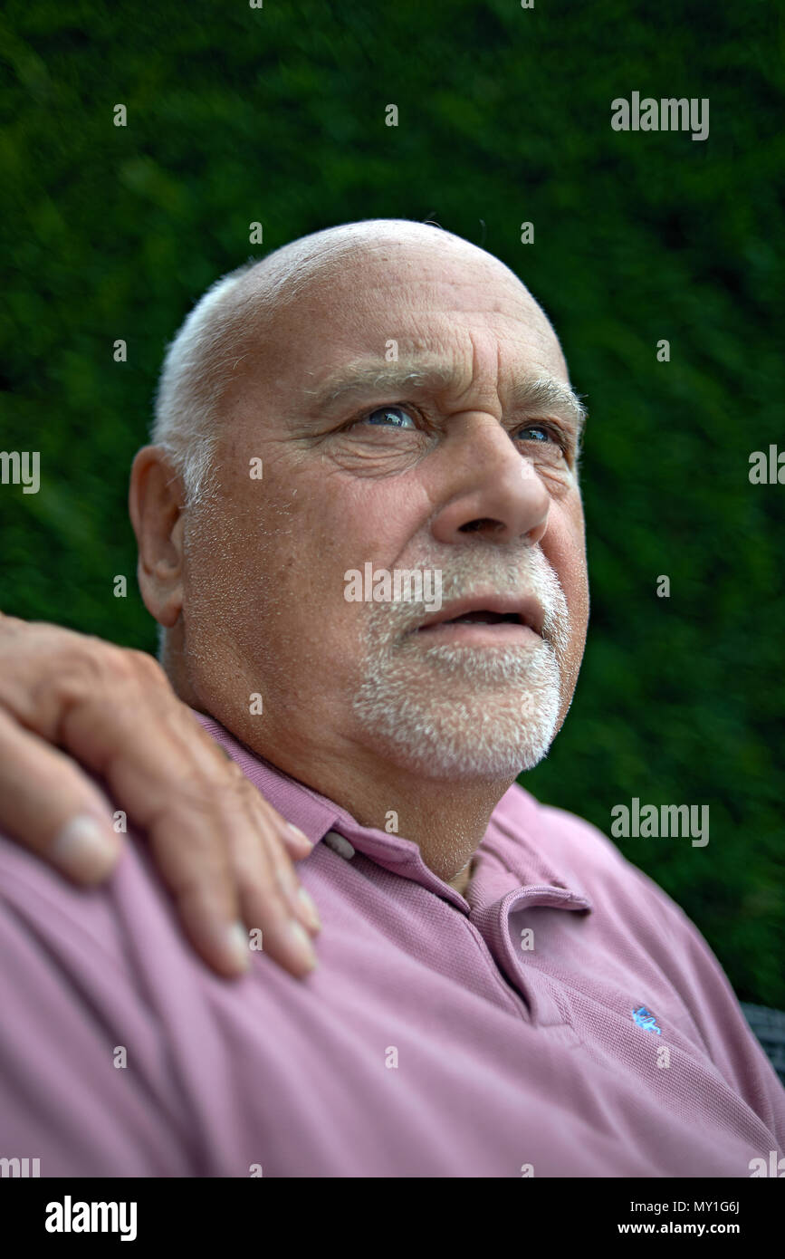 Portrait d'un homme âgé à la peur assis dehors dans le jardin avec la main de sa femme sur son épaule pour le réconforter en cas de besoin Banque D'Images