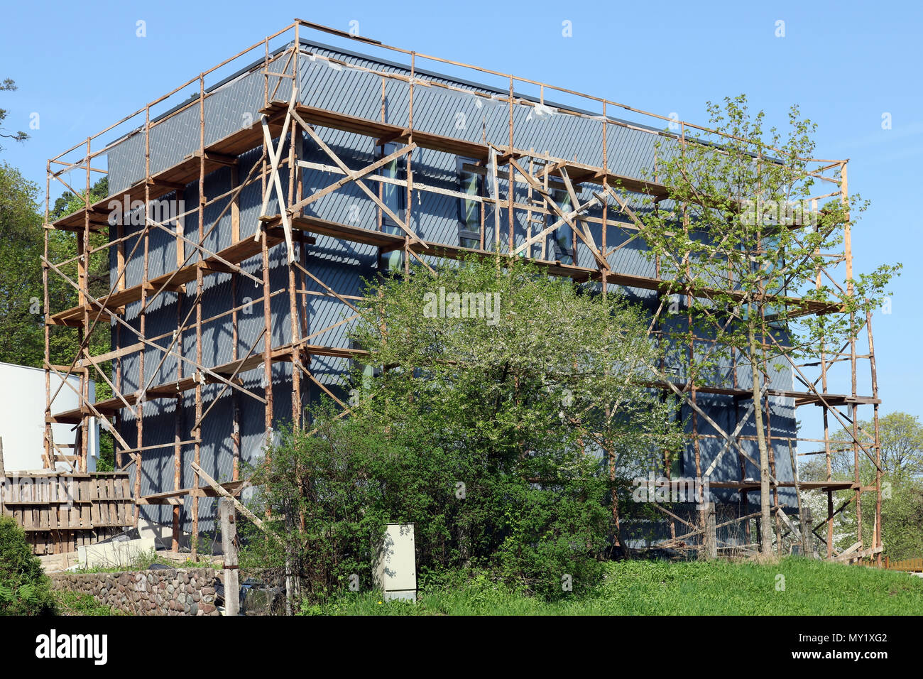 L'inachevé maison de village standard est en plastique panneaux ondulés, qui sont montés avec l'aide d'échafaudages en bois. Journée de printemps ensoleillée landsca Banque D'Images