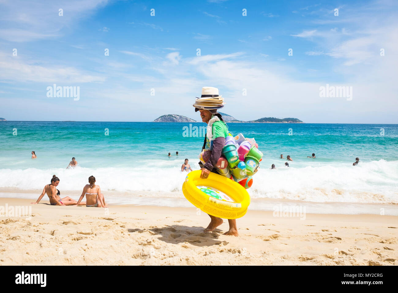 RIO DE JANEIRO, Brésil - circa 2017, février : Vendeur de plage de plage multicolores vente jouets et jeux gonflables transporte ses marchandises le long de la plage d'Ipanema. Banque D'Images
