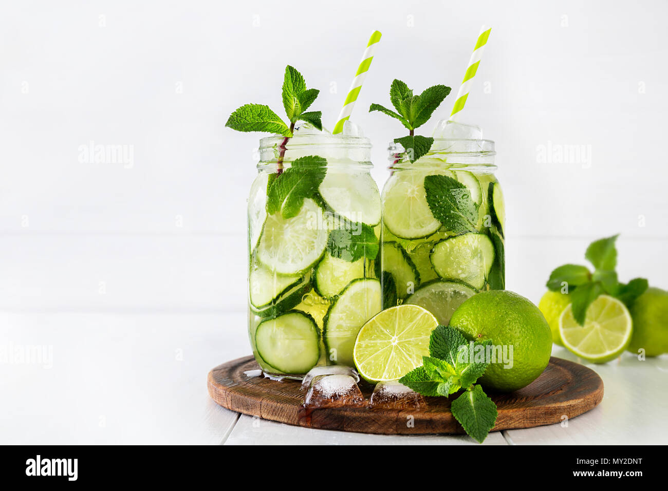 Deux bols de fruits et d'herbes de l'eau infusée avec le concombre, la Menthe et citron vert et des glaçons sur fond blanc. Le concept de la désintoxication et la perte de poids. Copier sp Banque D'Images