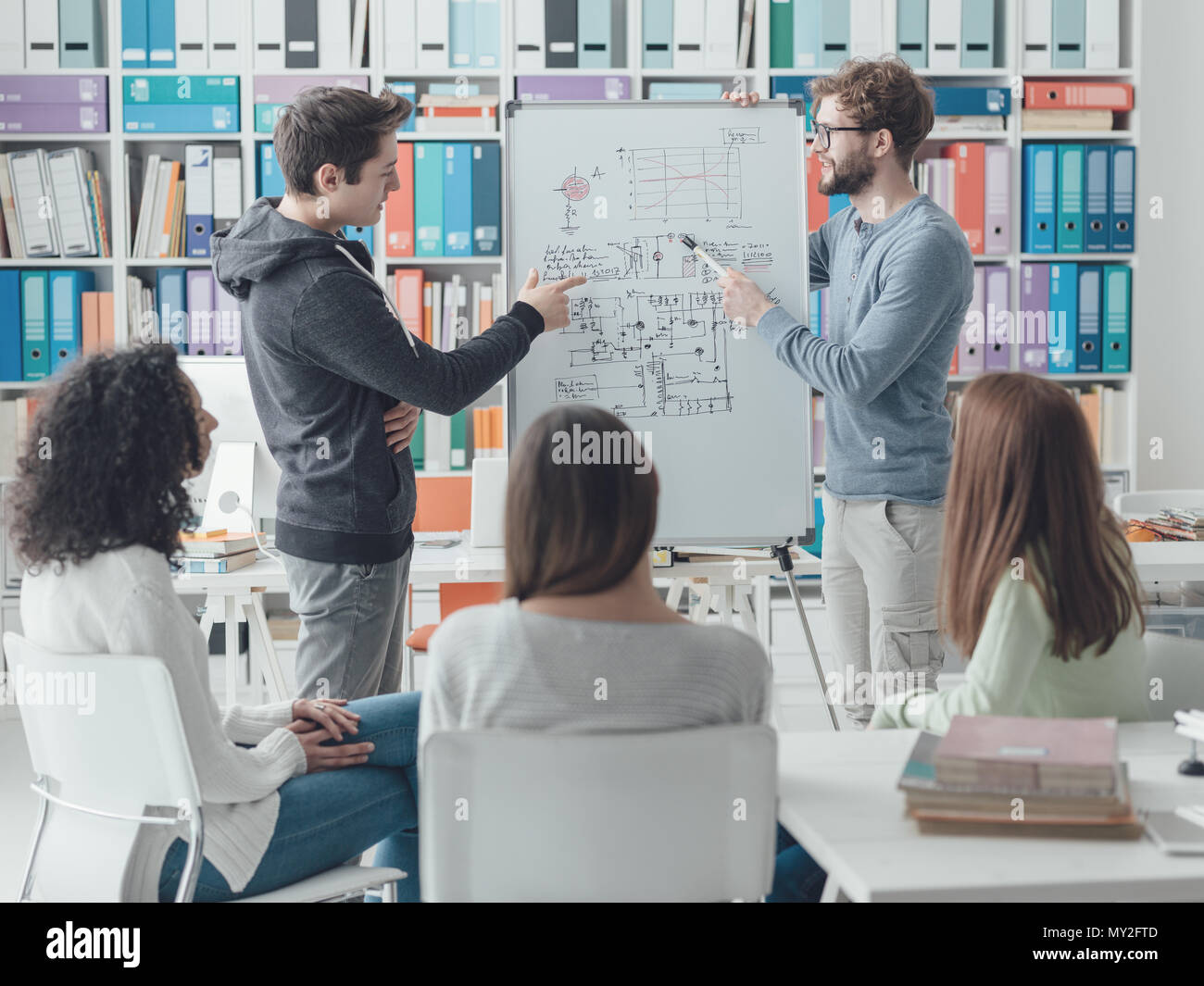 Jeune chercheur donnant un cours à un groupe d'étudiants universitaires, il est écrit sur un tableau blanc et de parler Banque D'Images