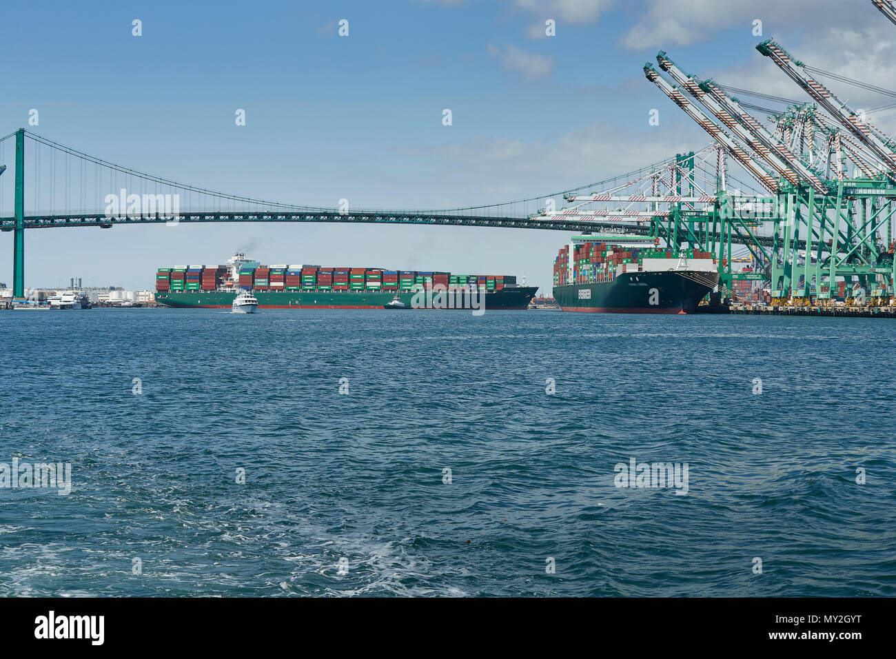 Le porte-conteneurs, SEAMAX NEW HAVEN, sont guidés par des remorqueurs du tracteur sous le Vincent Thomas Bridge dans le Port de Los Angeles, Californie, USA. Banque D'Images