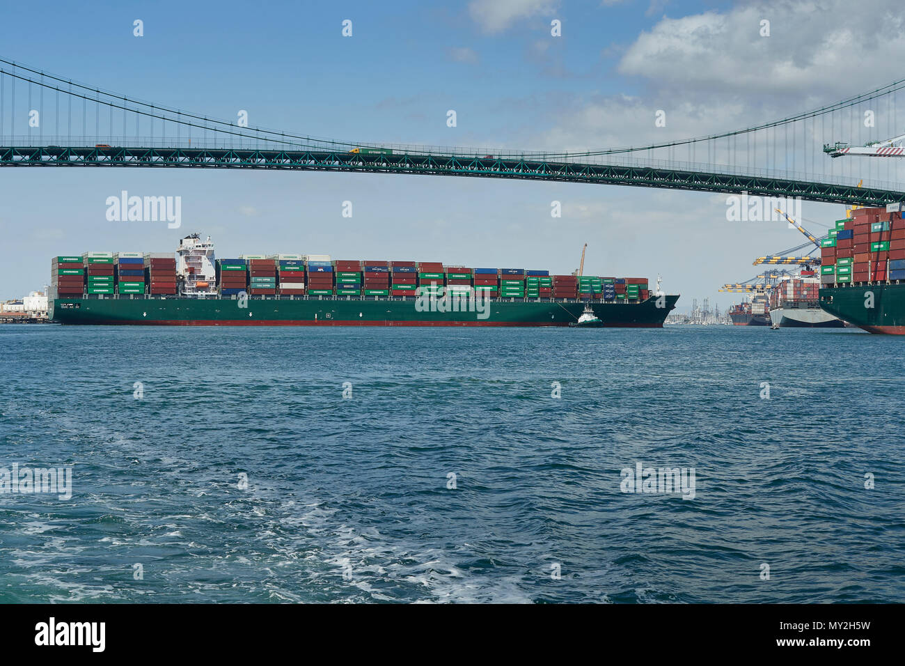 Le porte-conteneurs géant SEAMAX, NEW HAVEN, être transformé par des remorqueurs du tracteur sous le Vincent Thomas Bridge dans le Port de Los Angeles, Californie, USA. Banque D'Images
