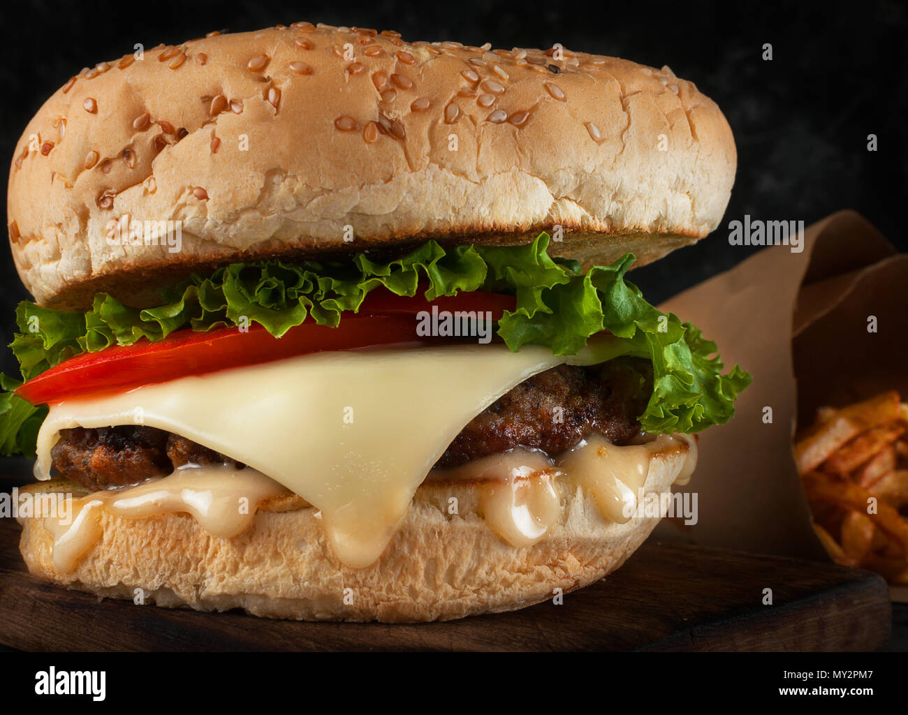 Un délicieux hamburger avec une escalope juteux, fromage, tomate et salade. Banque D'Images