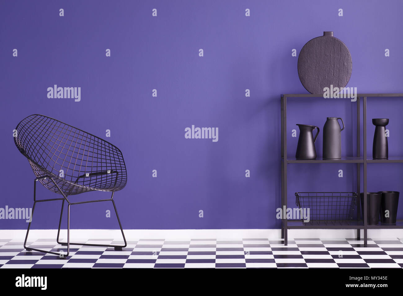 Fauteuil noir sur sol en damier en violet salon intérieur avec vase sur une étagère Banque D'Images