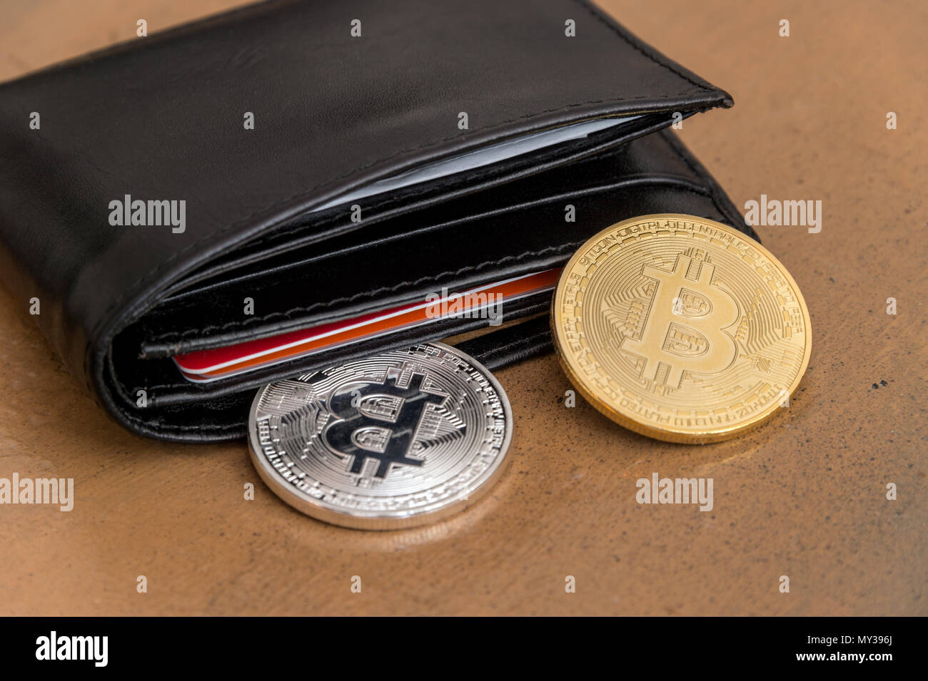 Deux pièces métalliques Bitcoin cryptocurrency sort une pochette en cuir Banque D'Images