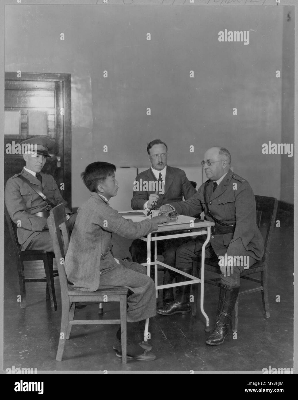 Les fonctionnaires de l'immigration des États-Unis d'examiner une nouvelle arrivée d'Asie, l'Angel Island, CA, 1923. Banque D'Images