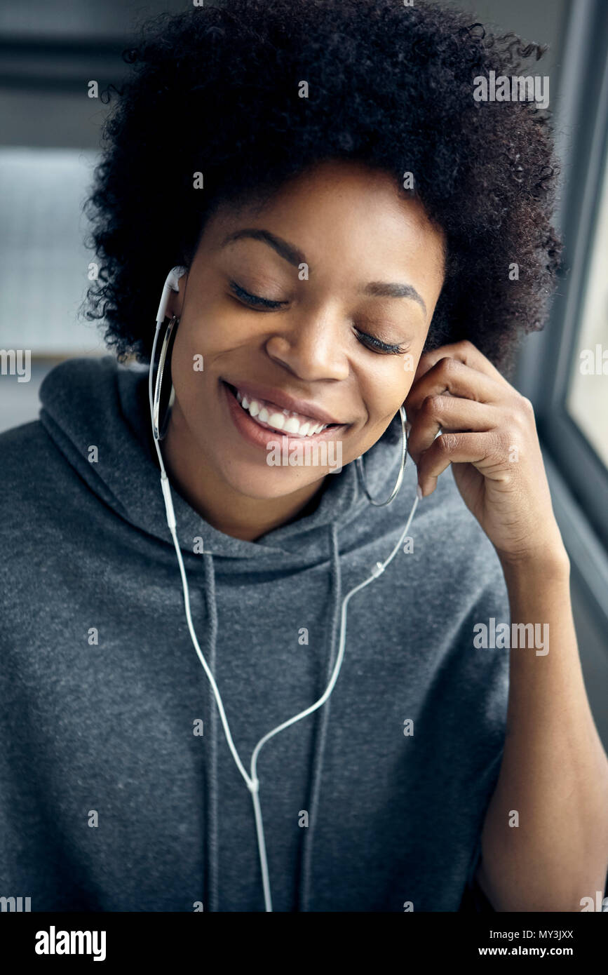 Young woman listening to earphones avec les yeux fermés Banque D'Images