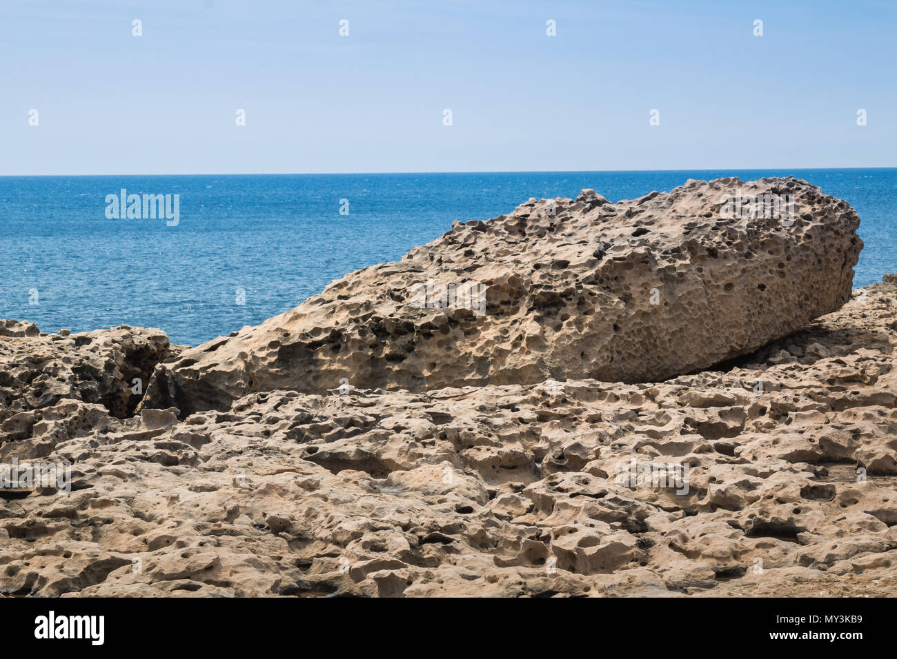 La surface de la structure de la roche, rappelant une terre de lune. Gros rocher sur le bord de mer. Horizon de la mer Méditerranée avec de petites vagues. Ciel bleu. Gozo, l'île Banque D'Images