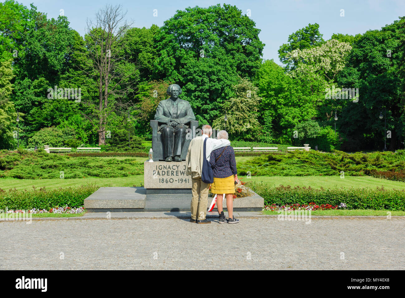 Une pause couple tout en flânant dans le parc Château Ujazdowski à Varsovie pour contempler une statue du compositeur et musicien Ignacy Paderewiski, Pologne. Banque D'Images