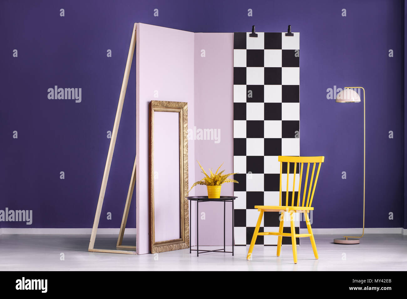 Chaise jaune à côté d'un tableau noir avec intérieur en studio et mur damier rose Banque D'Images