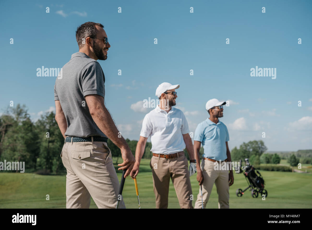 Les jeunes joueurs de golf multiethnique à l'écart en se tenant sur le terrain Banque D'Images