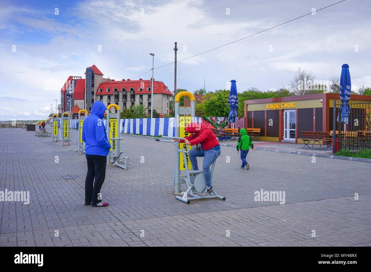 Zelenogradsk, Russie - 17 mai 2016 : un homme avec des enfants dans des vestes de couleur debout à la fonction gymnases waterfront city. Banque D'Images