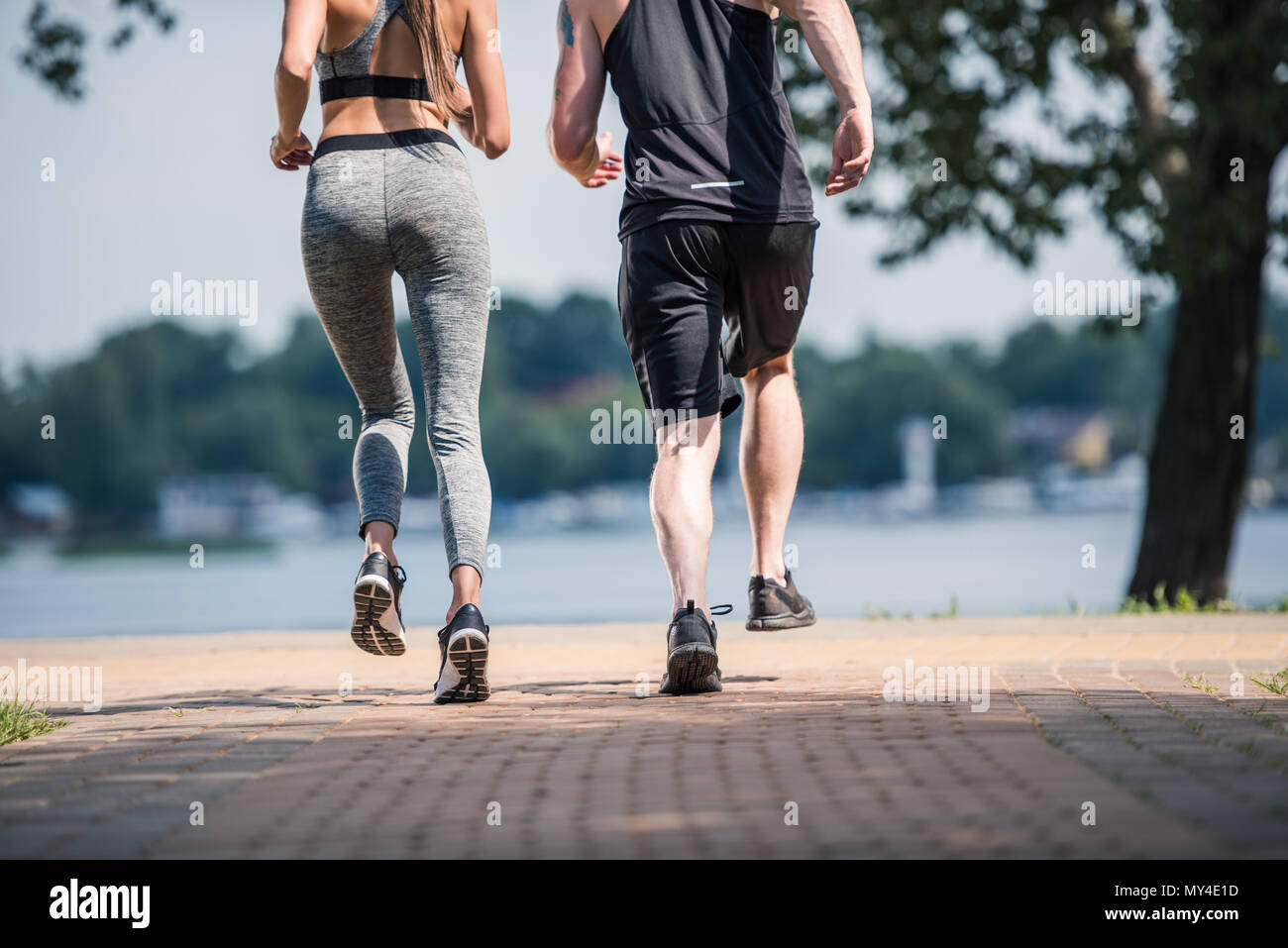 Vue partielle de la sportive couple jogging together in park Banque D'Images