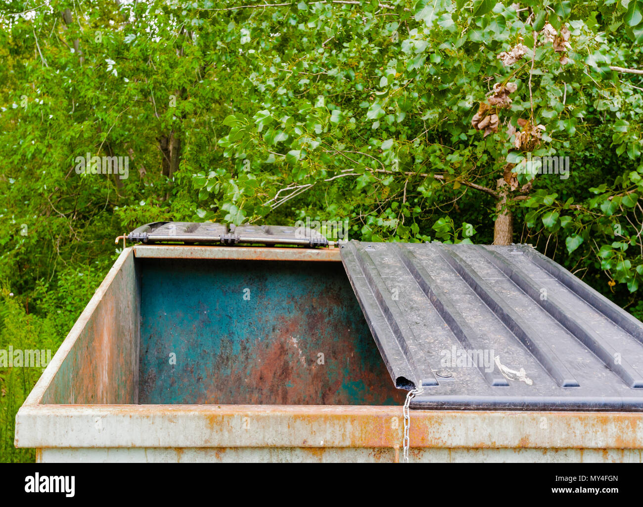 Grande sale vide du métal rouillé avec benne à couvercle semi-ouvertes près des arbres. Banque D'Images