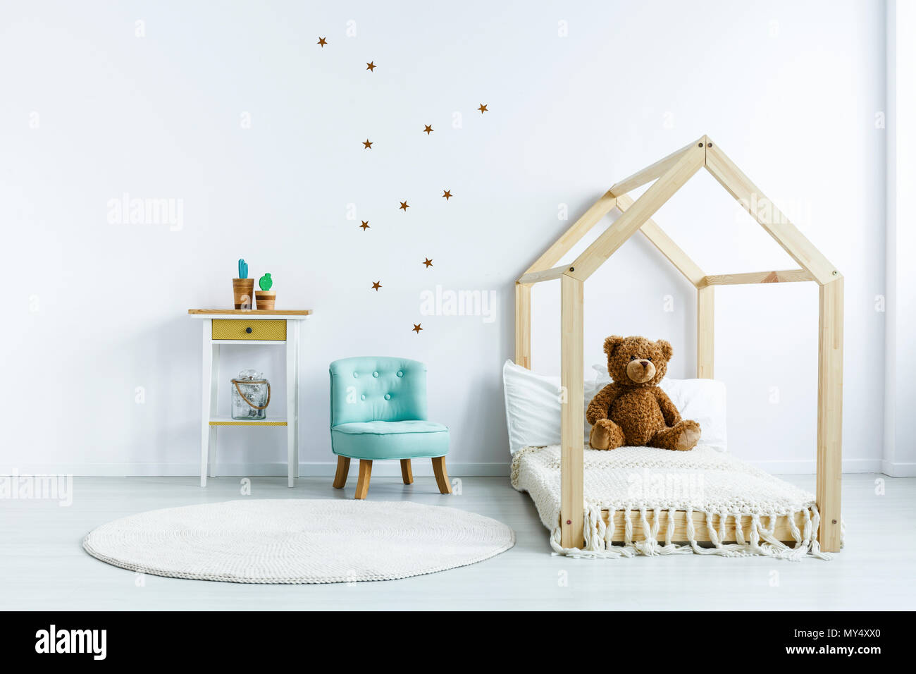 Ours sur lit en bois à côté du fauteuil bleu blanc dans la chambre de l'enfant intérieur. Photo réelle Banque D'Images