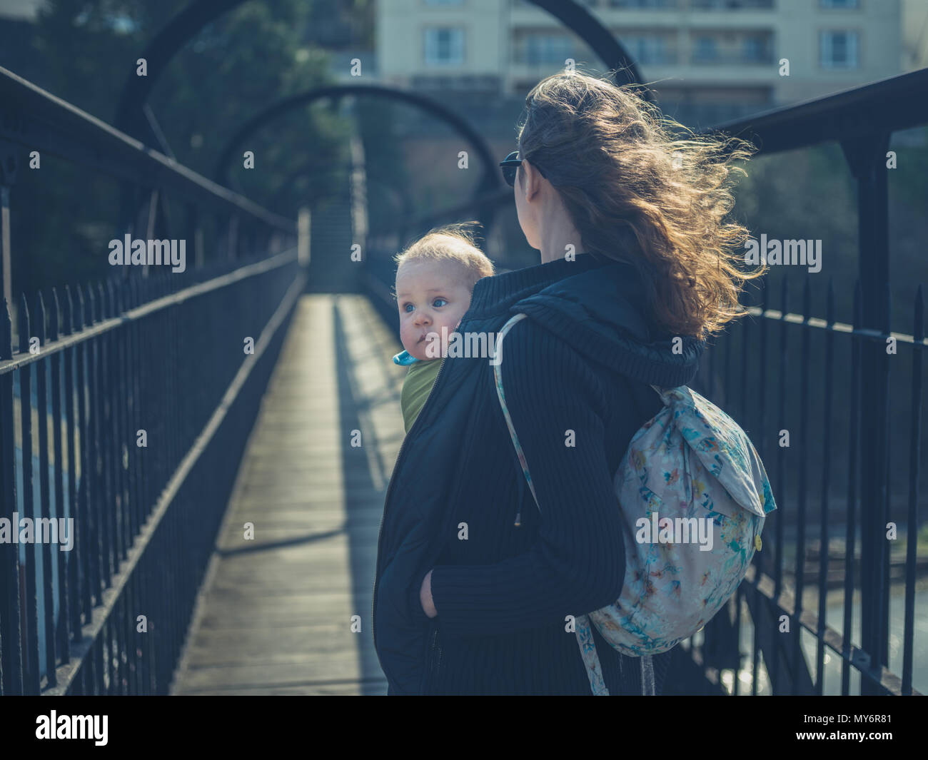 Une jeune mère est debout sur une passerelle avec son bébé dans une écharpe Banque D'Images