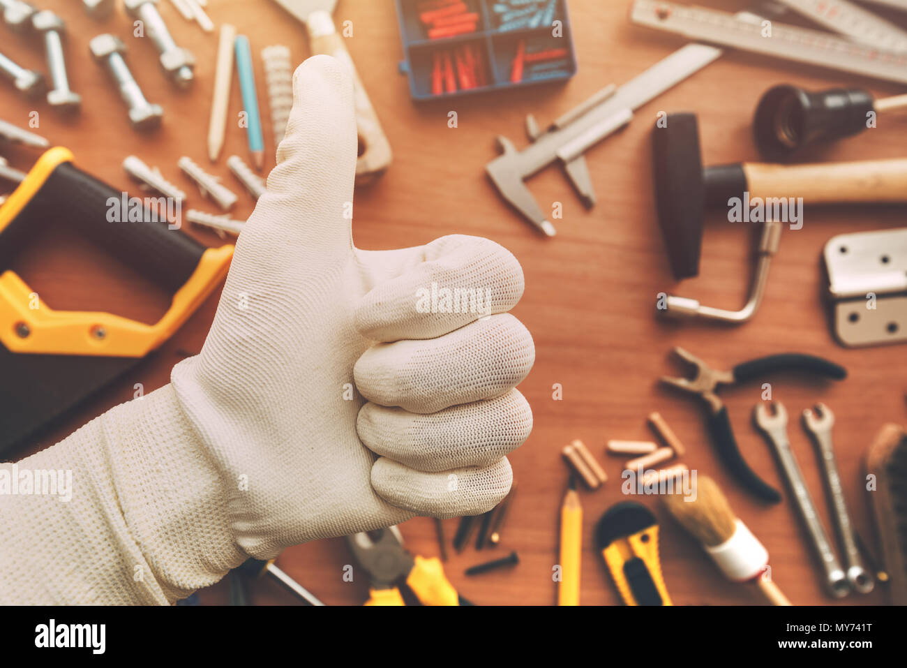 Thumb up signe de main d'approbation au cours de l'homme à l'entretien d'un bureau avec des outils de bricolage, vue du dessus Banque D'Images
