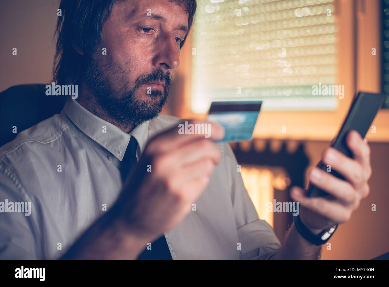Portrait des services bancaires mobiles application pour acheter en ligne avec carte de crédit et à l'intérieur du smartphone bureau sombre, selective focus Banque D'Images