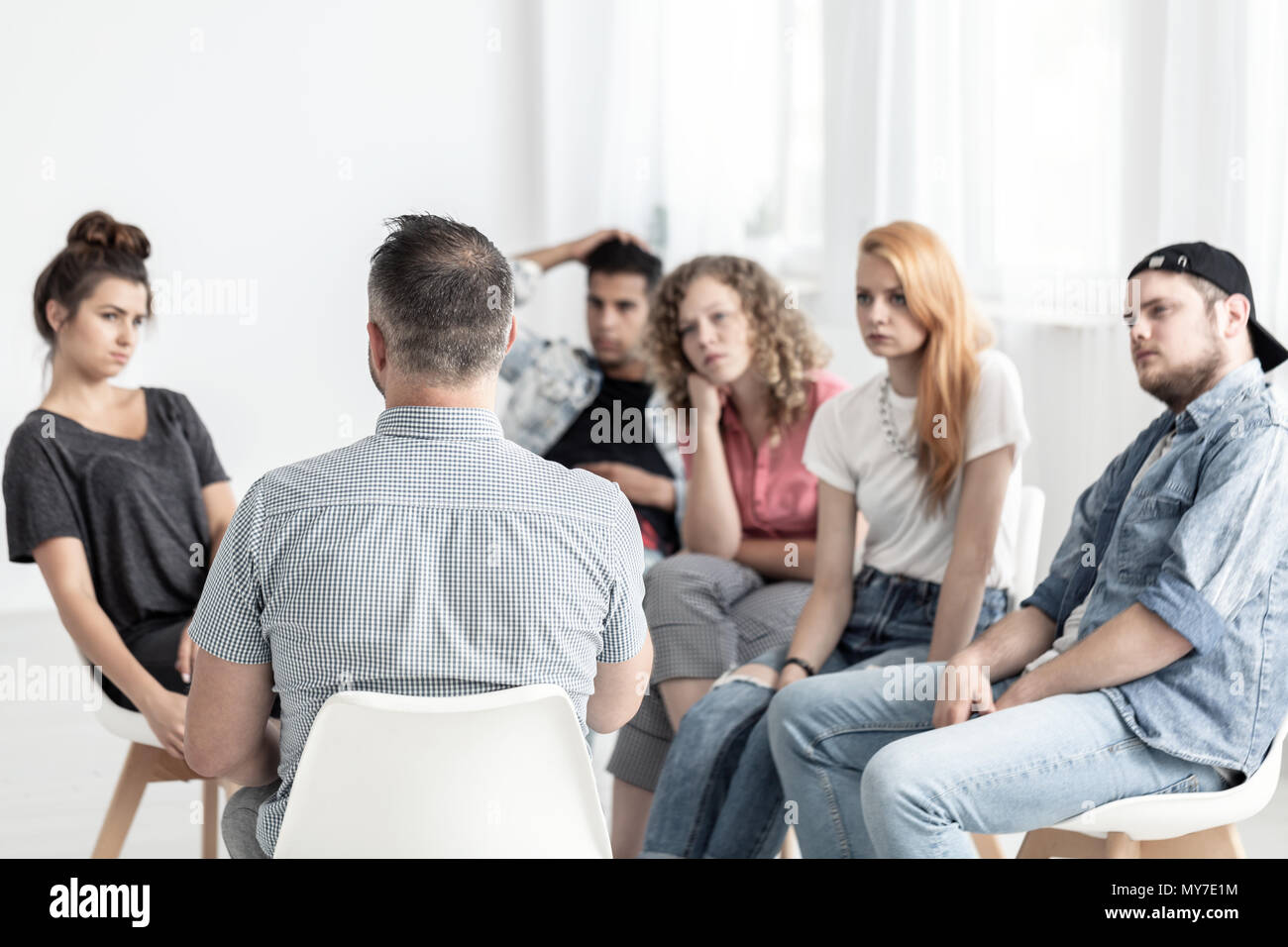 Groupe de jeunes de parler à un psychologue dans un centre de réadaptation Banque D'Images
