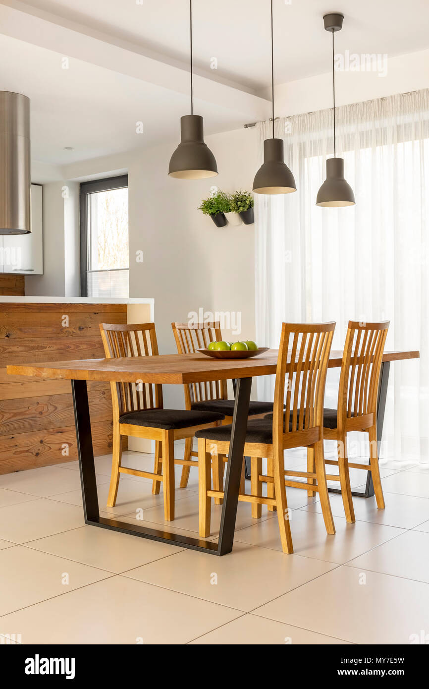 Lampes au-dessus de table et chaises en bois dans la salle à manger lumineuse minimale de l'intérieur. Photo réelle Banque D'Images