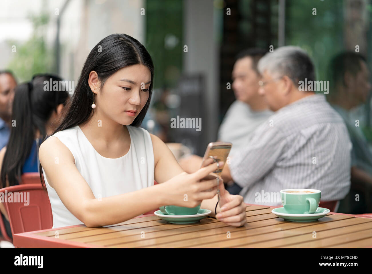 Businesswoman sitting outdoors, au cafe, using smartphone Banque D'Images